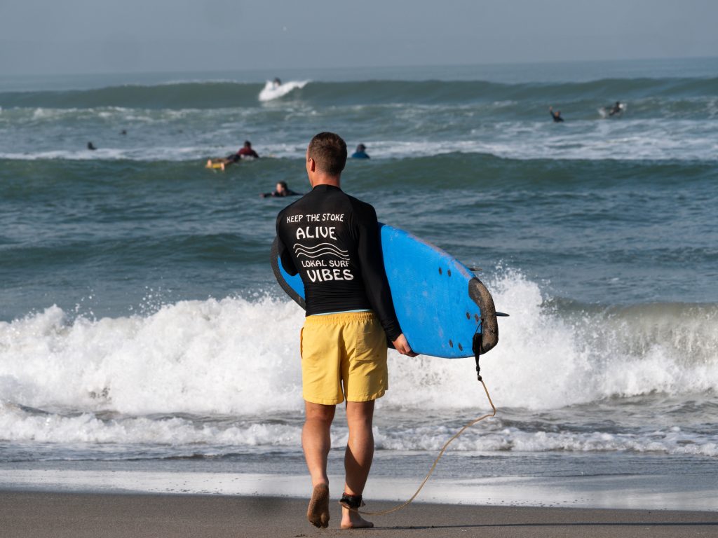 Samuel Lehner mit Surfbrett am Meer
